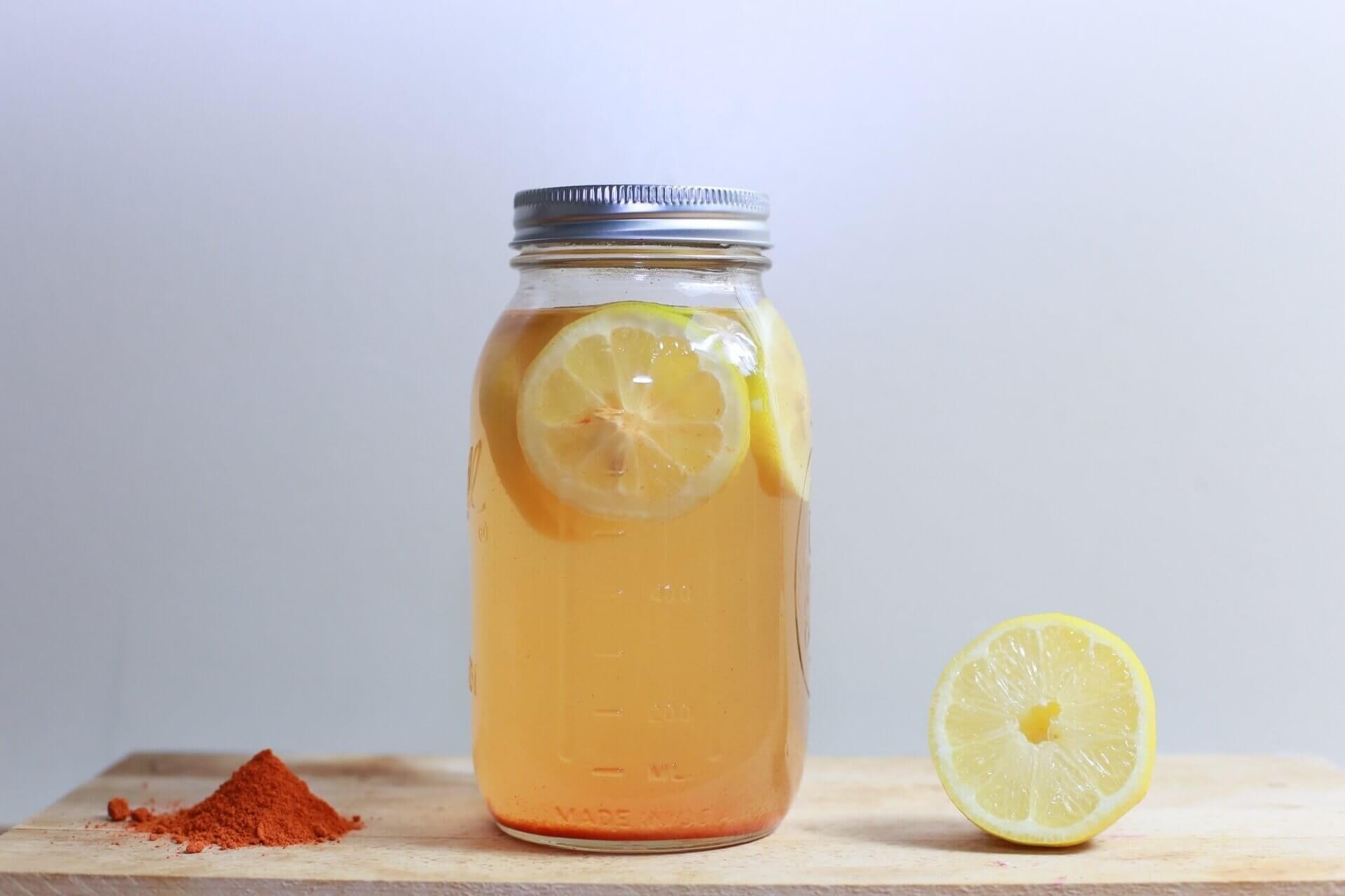 Mason jar filled with lemon water and cayenne powder.